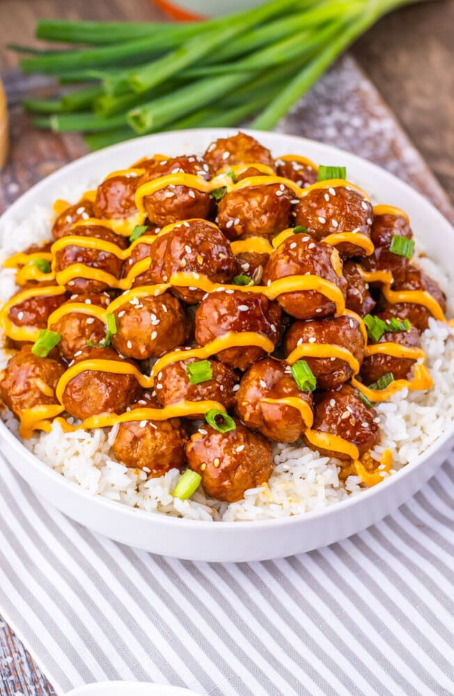 Slow cooker Korean BBQ meatballs with sesame seeds and peppers over rice on white plate