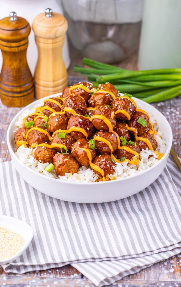 Slow cooker Korean BBQ meatballs over white rice garnished with peppers and green onions