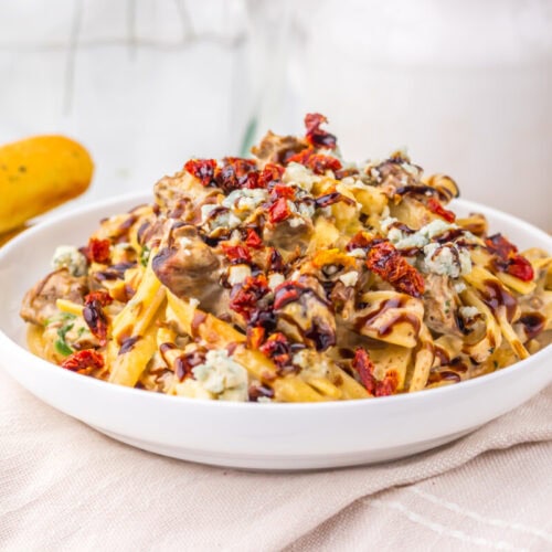 Slow Cooker Olive Garden Steak Gorgonzola pasta with creamy sauce, mushrooms, and crispy topping in white bowl