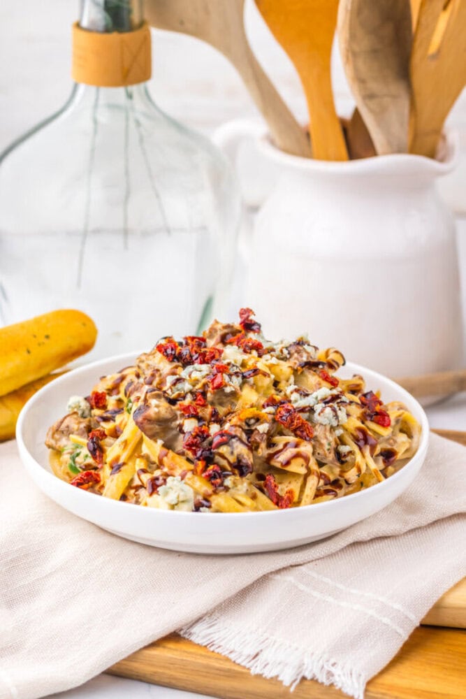 Slow Cooker Copycat Olive Garden Steak Gorgonzola pasta with fettuccine, mushrooms, sun-dried tomatoes and cheese in white bowl
