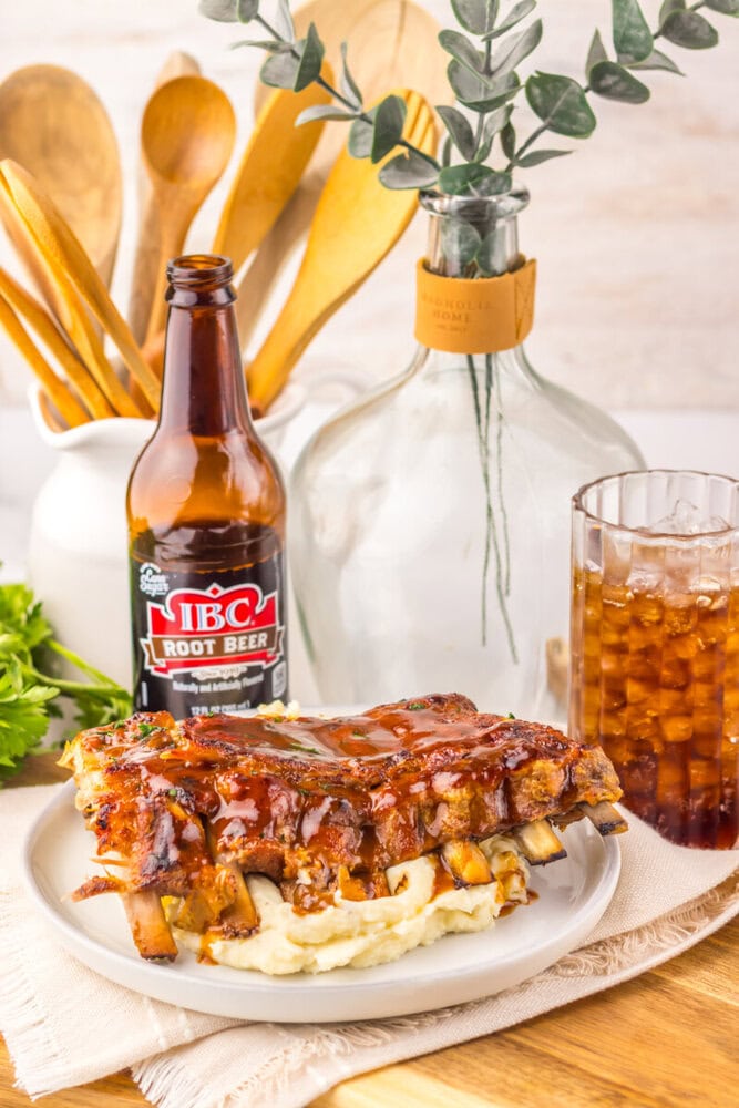 Slow cooker root beer BBQ ribs plated with mashed potatoes, root beer bottle and glass