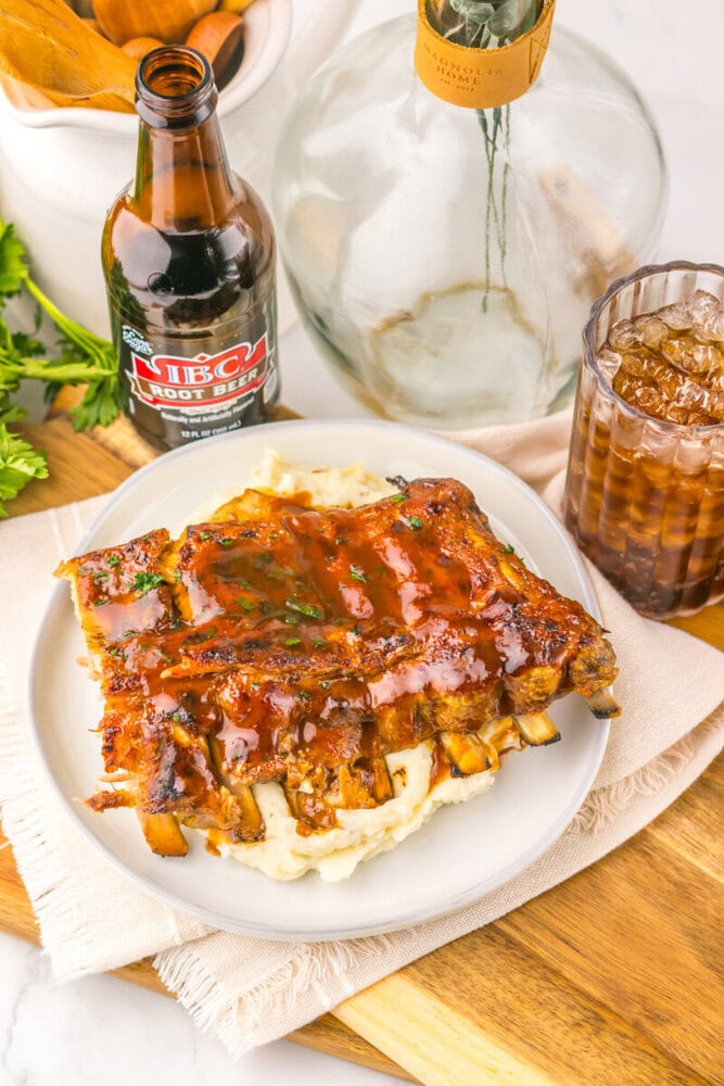 Slow cooker root beer BBQ ribs plated on mashed potatoes with root beer beverage