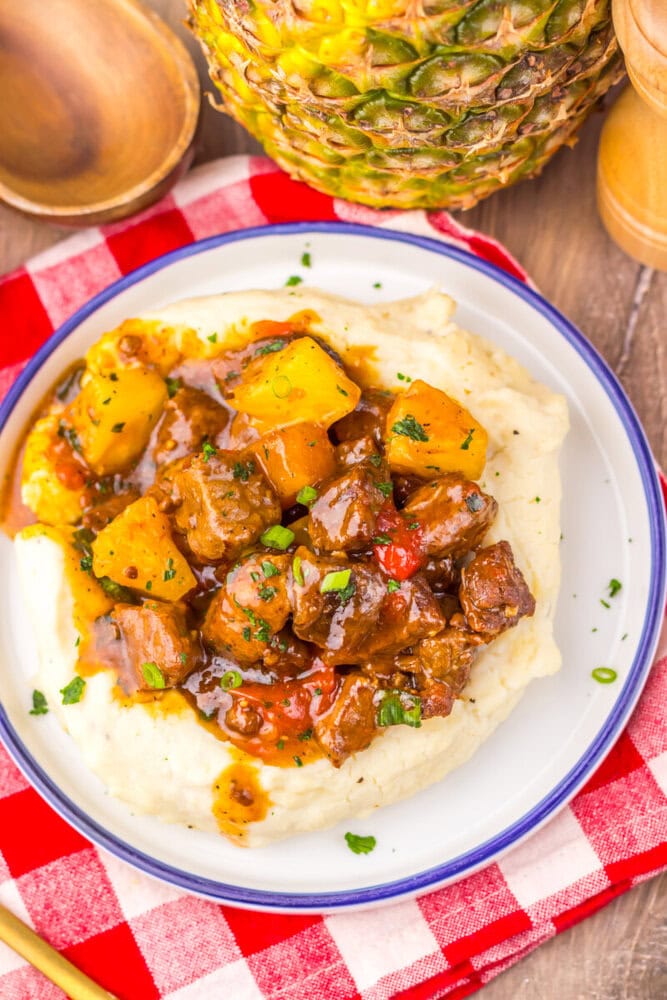 Slow cooker sweet chili pineapple steak tips served over mashed potatoes with caramelized pineapple and green onions