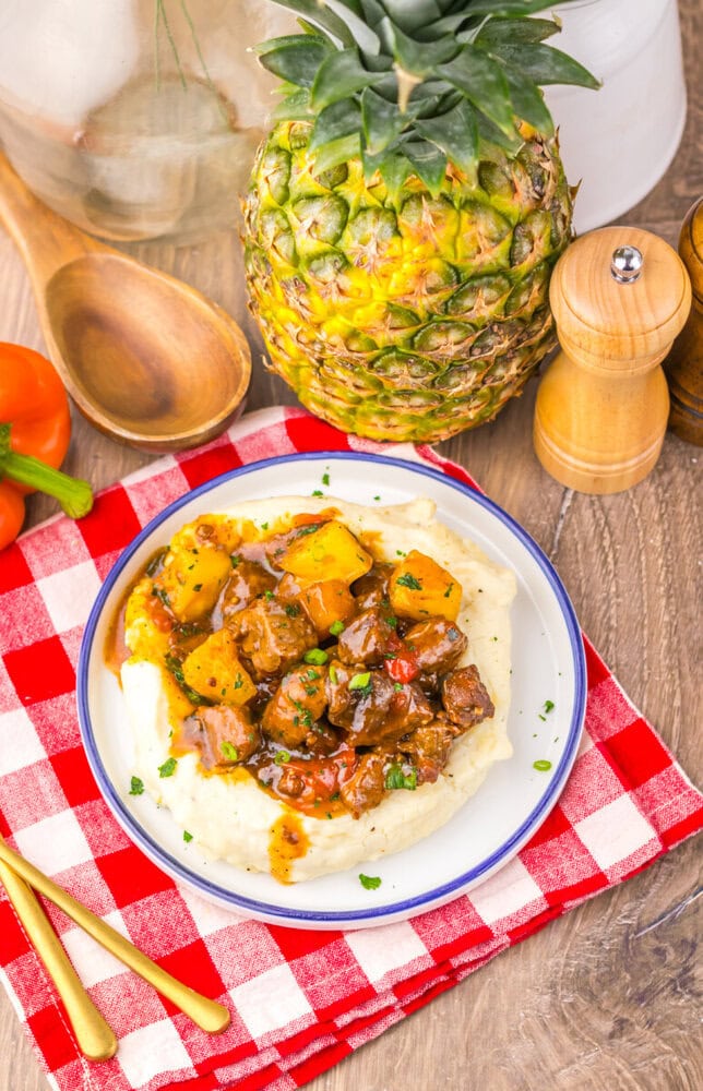Slow cooker sweet chili pineapple steak tips served over mashed potatoes with fresh pineapple garnish