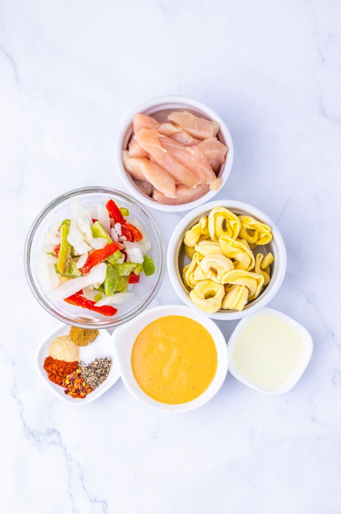 Southwest Ranch Chicken Tortellini ingredients prepped in bowls including chicken, peppers, onion, cereal rings, spices, and sauce