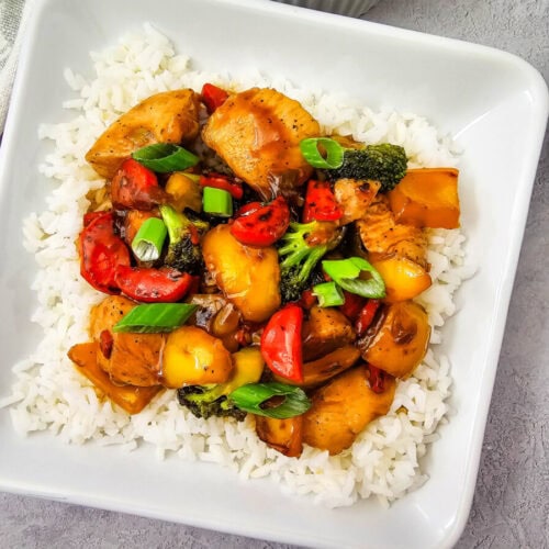 Teriyaki chicken and rice bowl with stir-fried vegetables and green onion garnish served in white bowl