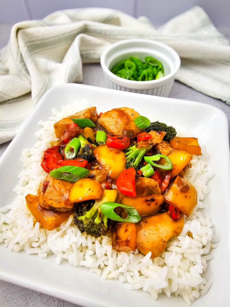 Teriyaki chicken and rice bowl with broccoli, bell peppers, and green onion garnish served on white rice