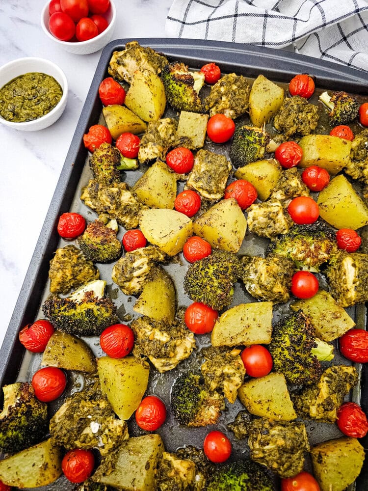 Sheet pan pesto chicken with roasted potatoes and tomatoes, fully cooked and ready to serve