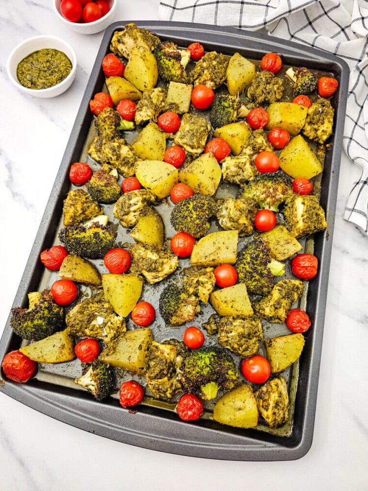 Sheet pan pesto chicken with roasted potatoes and cherry tomatoes on parchment paper