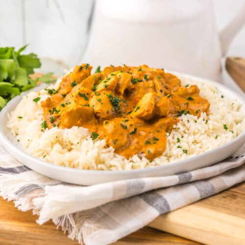 Slow cooker chicken tikka masala served over rice with cilantro garnish on white plate