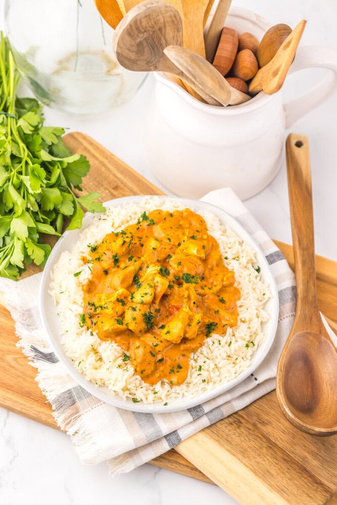 Slow Cooker Chicken Tikka Masala served over rice with cilantro garnish on white plate