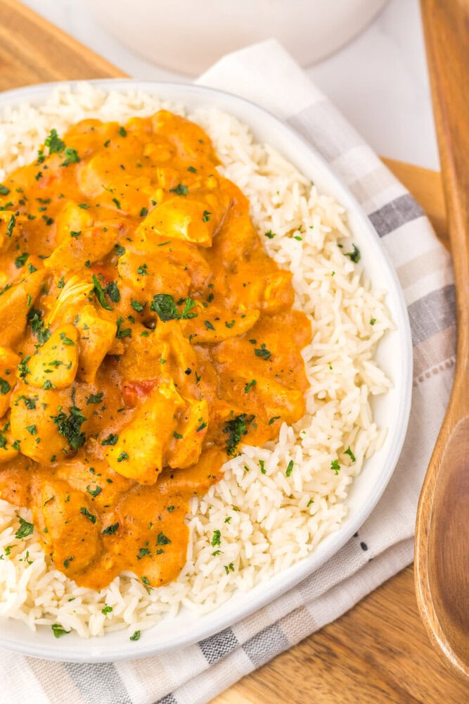 Slow cooker chicken tikka masala with creamy orange sauce served over white rice garnished with fresh parsley