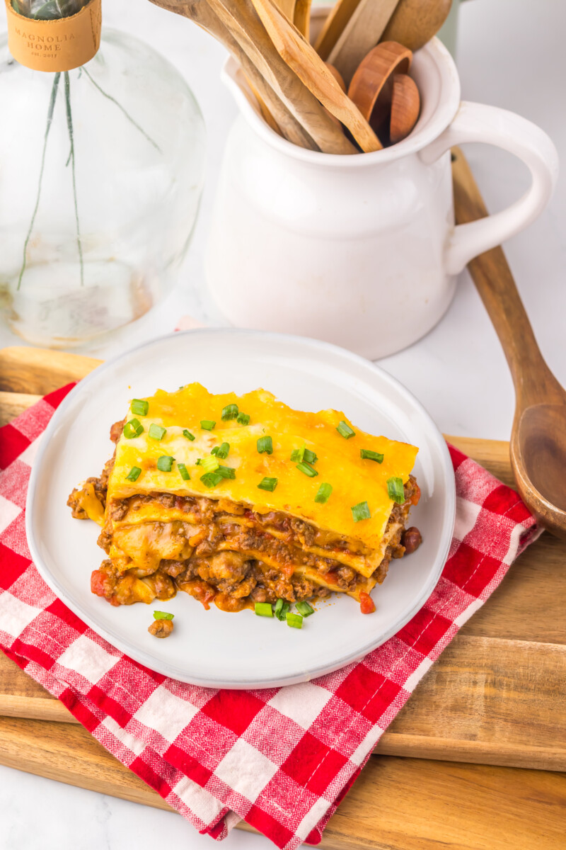 Slow cooker chili cheese enchilada bake plated on white dish with melted cheddar cheese and sliced green onions