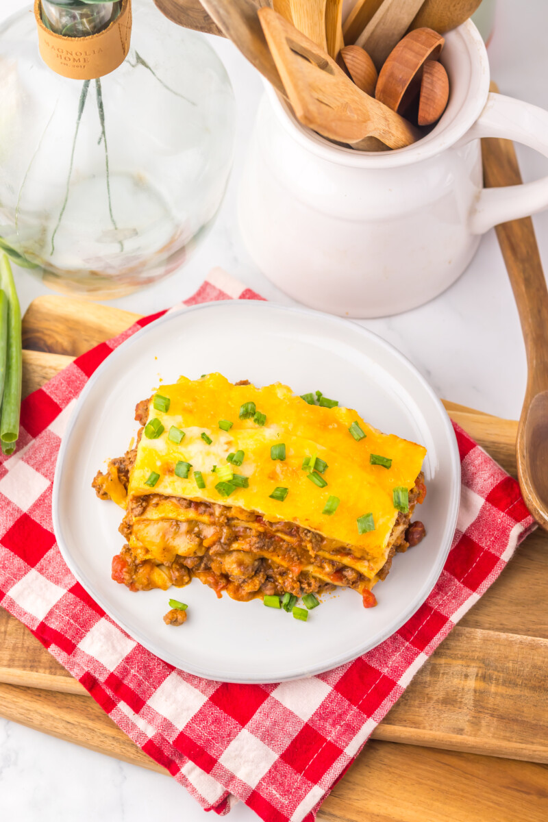 Slow cooker chili cheese enchilada bake plated with melted cheddar cheese and fresh green onions