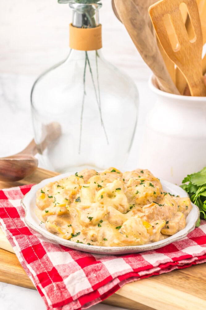 Slow cooker French onion chicken tortellini plated and garnished with fresh herbs on white plate