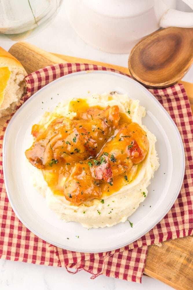 Slow cooker maple bacon chicken with mashed potatoes, garnished with parsley and cracked pepper
