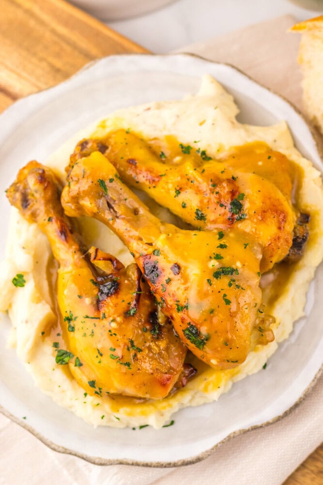 Slow cooker maple Dijon chicken legs served over mashed potatoes with parsley garnish