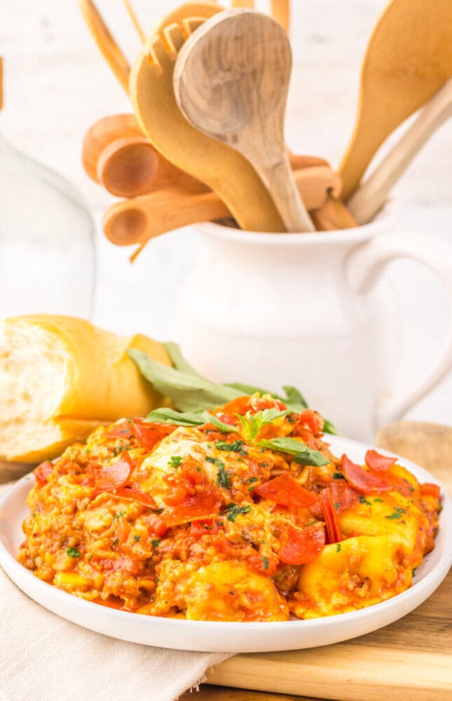 Slow cooker pizza ravioli plated with fresh basil garnish and lemon wedges