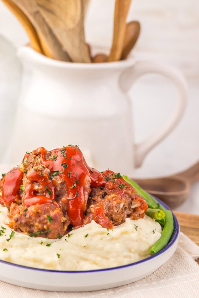 Slow cooker porcupine meatballs plated on mashed potatoes with fresh parsley garnish