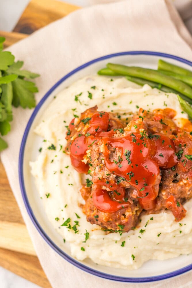 Slow cooker porcupine meatballs with red peppers served on mashed potatoes with green beans and fresh parsley garnish