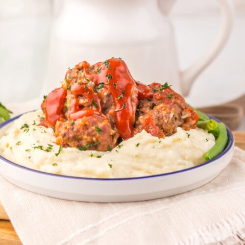 Slow cooker porcupine meatballs plated with mashed potatoes and red pepper garnish