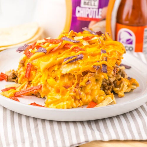 Slow Cooker Taco Bell Grilled Cheese Burrito Casserole topped with melted cheese and bacon, plated and ready to serve