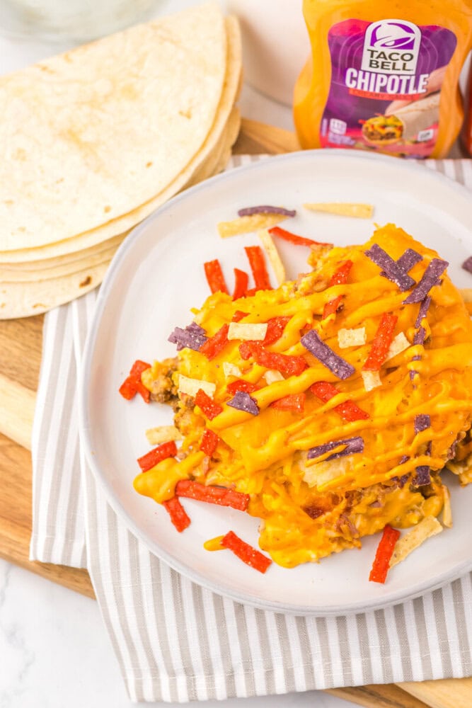 Slow cooker Taco Bell copycat grilled cheese burrito casserole topped with melted cheddar cheese and fresh toppings, plated and ready to serve