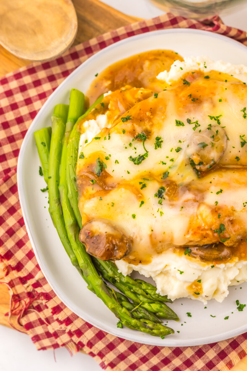 Slow cooker smothered chicken with cheese and mushrooms served with mashed potatoes and asparagus