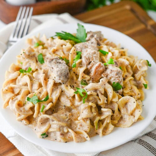 Slow cooker creamy beef and noodles plated on white dish with parsley garnish