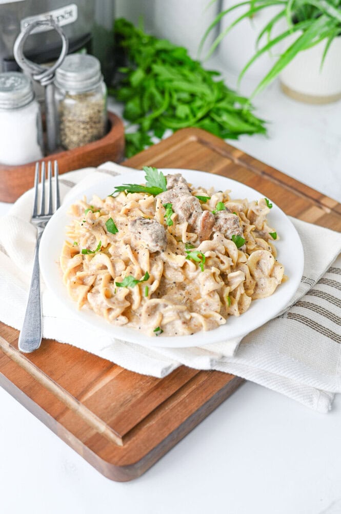 Slow cooker creamy beef and noodles plated on white dish with parsley garnish