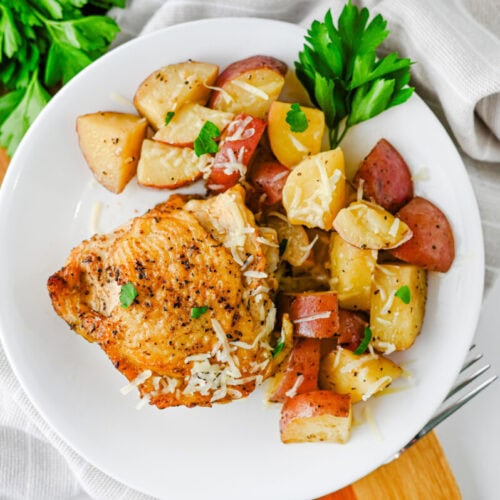 Slow cooker garlic parmesan chicken with roasted potatoes and sausage plated on white dish