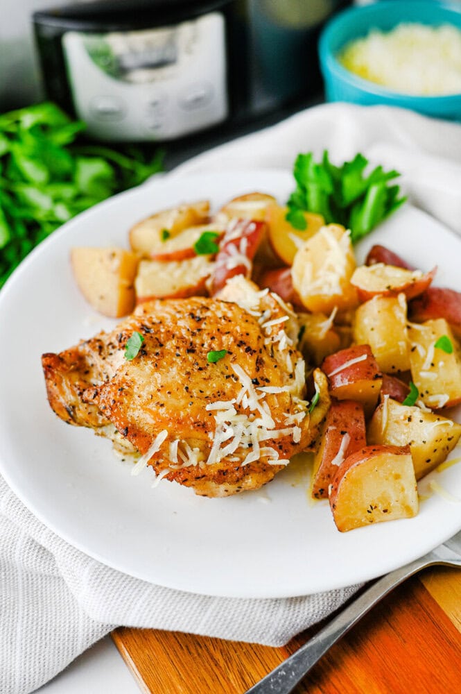Slow cooker garlic Parmesan chicken and potatoes plated on white dish with Parmesan garnish