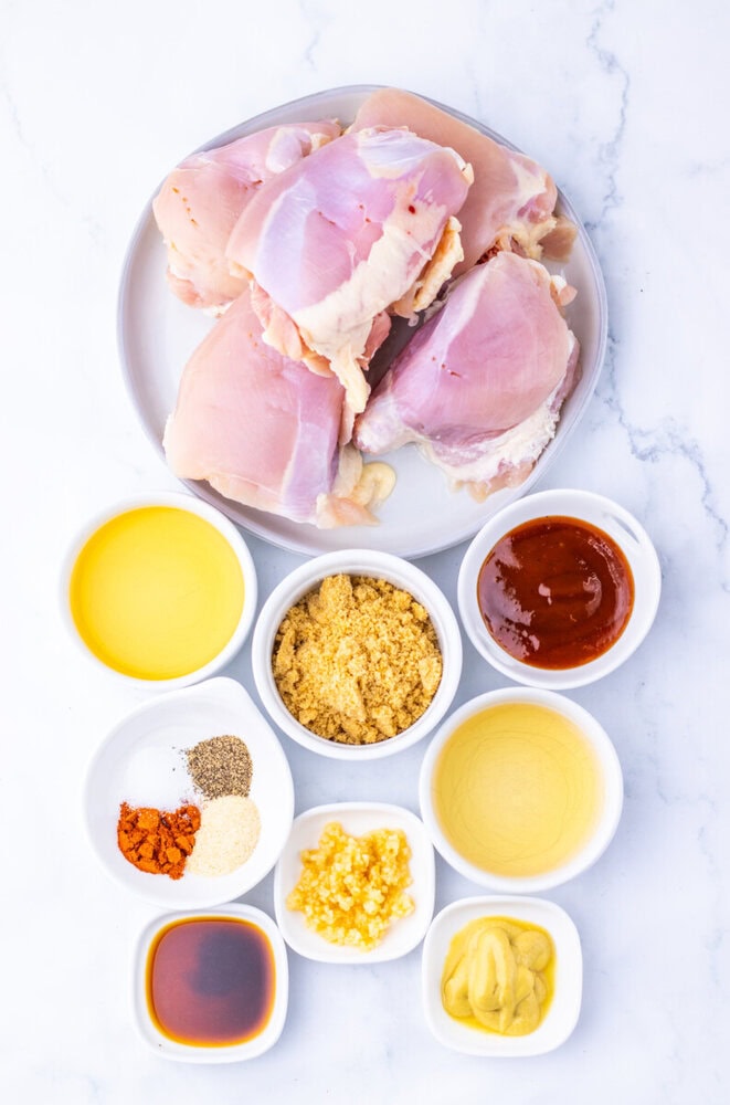 Apple Cider BBQ Pulled Chicken ingredients laid out including raw chicken breasts, oils, spices, brown sugar, mustard and barbecue sauce