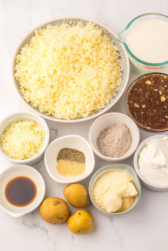 Ingredients for Cheesy French Onion Potato Casserole laid out including shredded potatoes, cheese, cream, broth, and seasonings