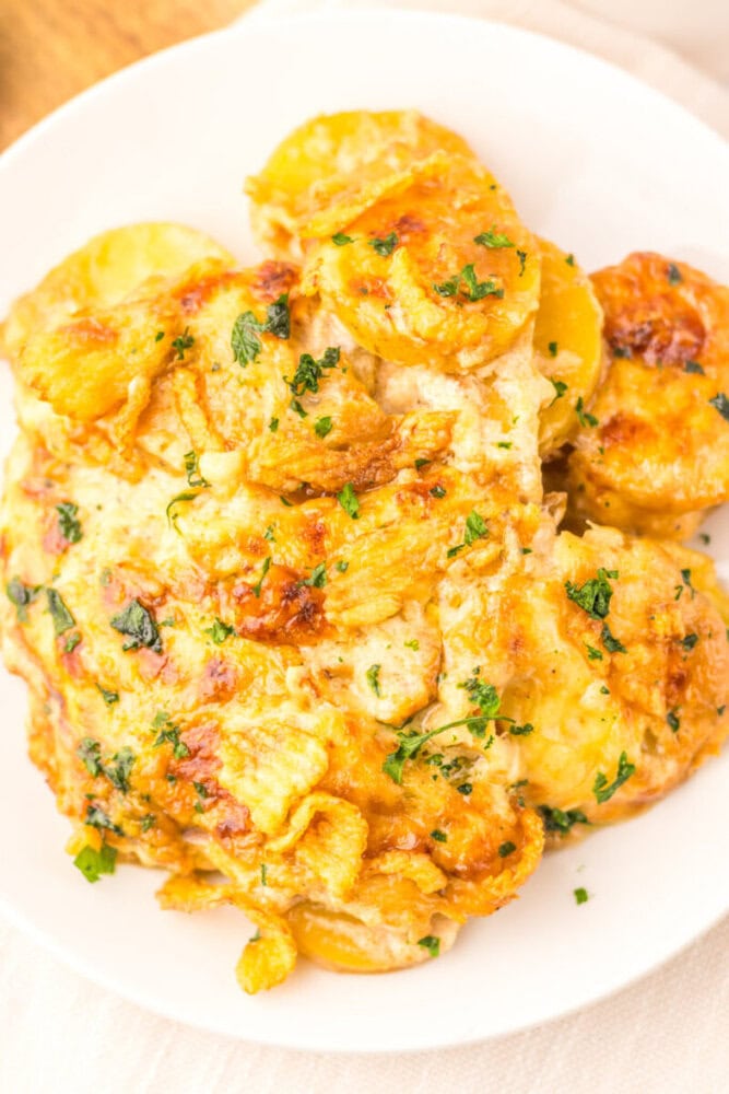 Cheesy French Onion Potato Casserole with golden melted cheese and parsley garnish on white plate