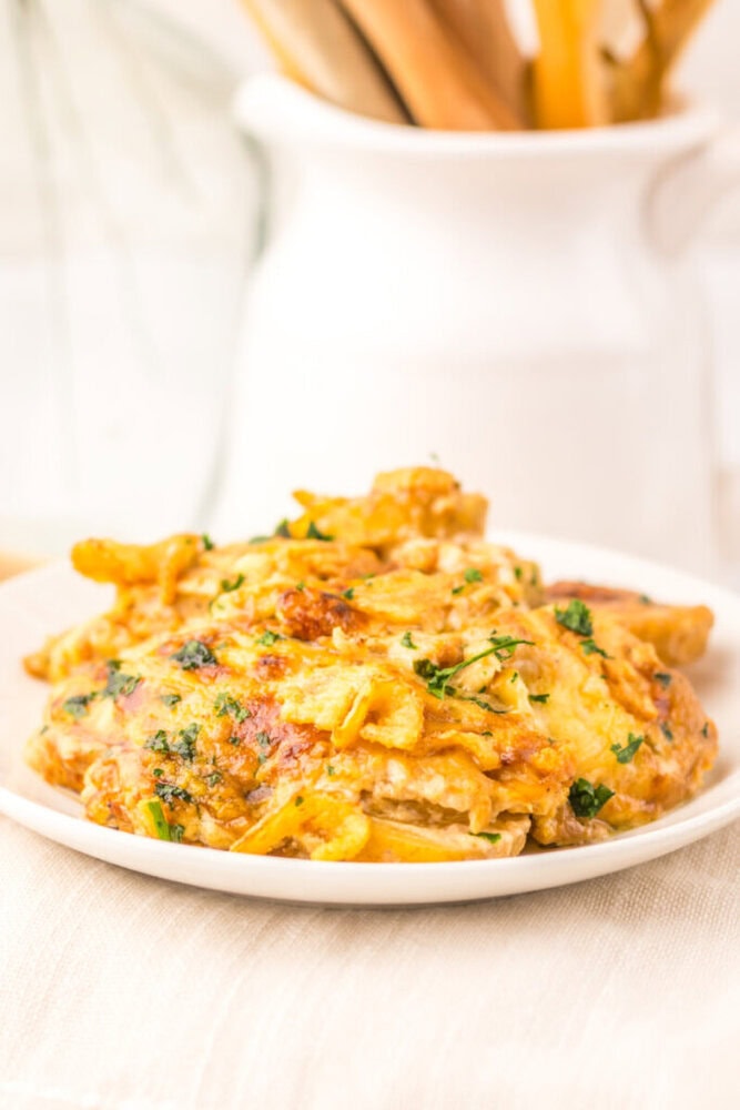 Cheesy French Onion Potato Casserole with melted cheese and parsley garnish on white plate