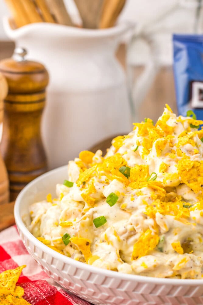 Cool Ranch Dorito Potato Salad in white bowl topped with crushed yellow chips and green onions
