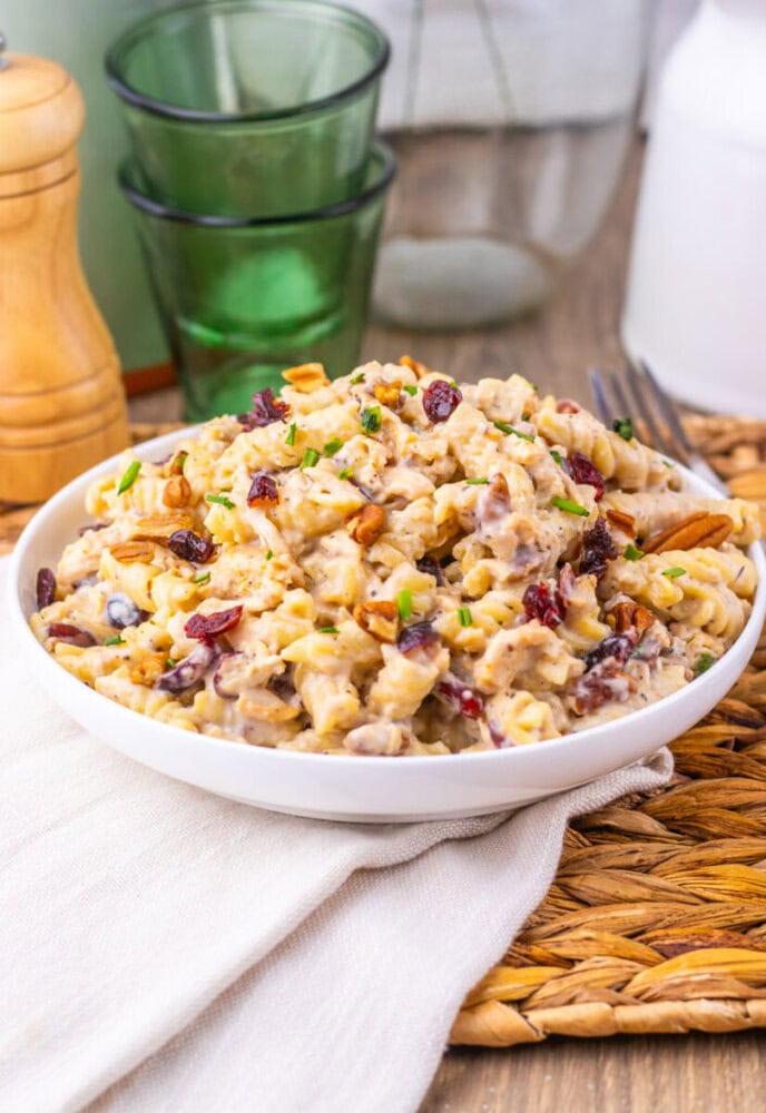 Cranberry White Cheddar Chicken Pasta salad in white bowl with walnuts and green onions garnish