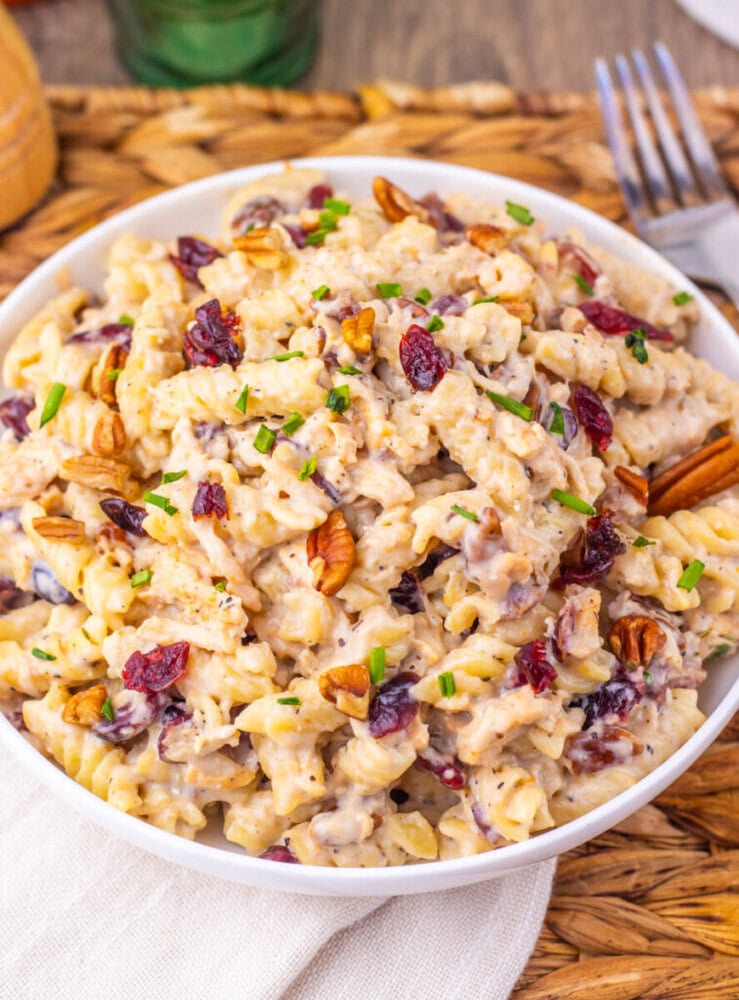 Cranberry White Cheddar Chicken Pasta salad with pecans and chives in white bowl