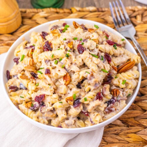 Cranberry White Cheddar Chicken Pasta salad with pecans and chives in white bowl on wooden table