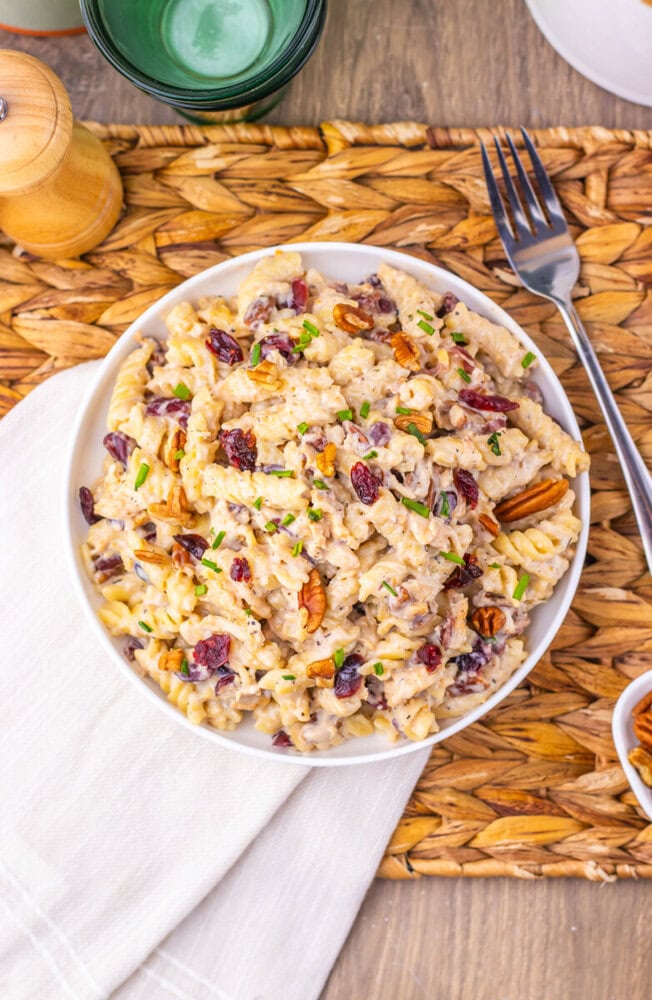 Cranberry White Cheddar Chicken Pasta salad with pecans and green onions on white plate