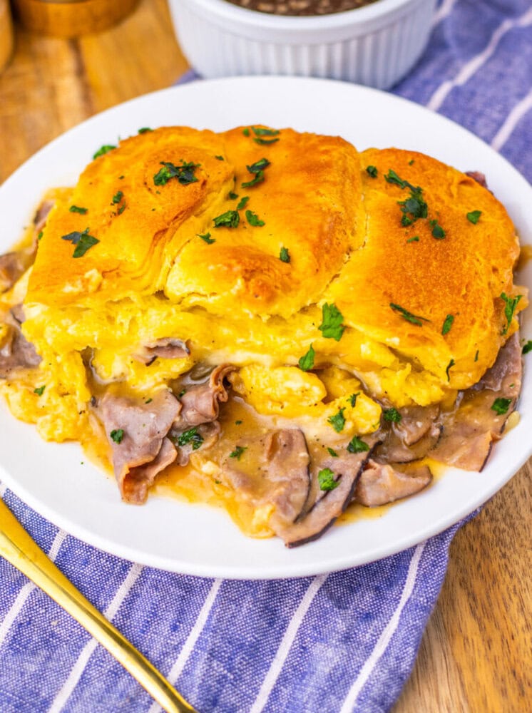 French Dip Biscuit Casserole with golden biscuit top, roast beef, and melted cheese garnished with parsley