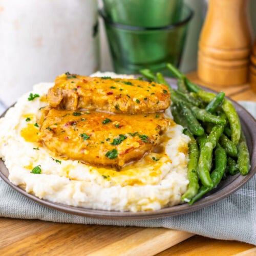 Maple Dijon pork chops plated on mashed potatoes with green beans garnish