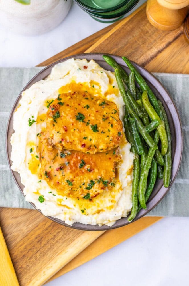 Maple Dijon Pork Chop with mashed potatoes and green beans plated on a gray bowl