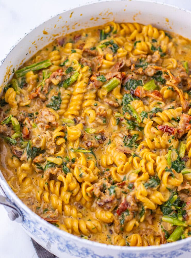One pot Zuppa Toscana pasta cooking in progress with ground meat, spinach, and rotini in creamy sauce