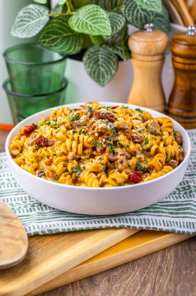 One Pot Zuppa Toscana Pasta - finished dish with rotini, sausage, bacon and fresh parsley in white bowl