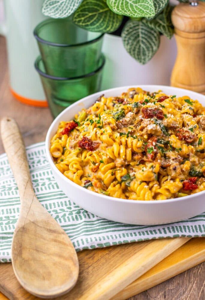 One Pot Zuppa Toscana Pasta with ground meat, bacon bits, and fresh parsley in white serving bowl