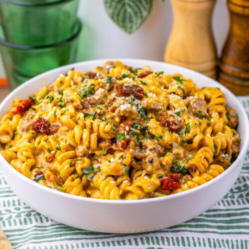One Pot Zuppa Toscana Pasta with ground meat, bacon bits, and fresh parsley in a white bowl