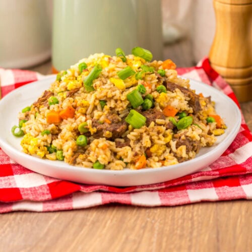 Slow cooker beef fried rice plated with vegetables and garnish, ready to serve