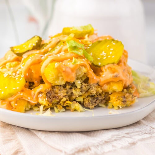 Slow Cooker Big Mac Tater Tot Casserole with ground beef, cheese, pickles, and crispy onions on white plate